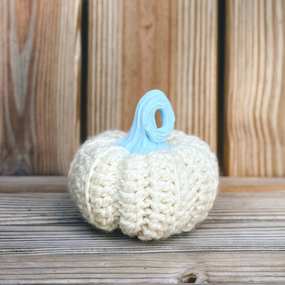 Knitted pumpkin with a blue stem on a wooden surface
