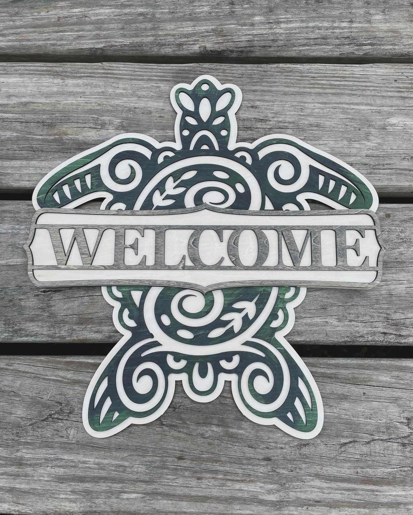 Sea turtle welcome sign stained with blue, green and grey shades with a plank background