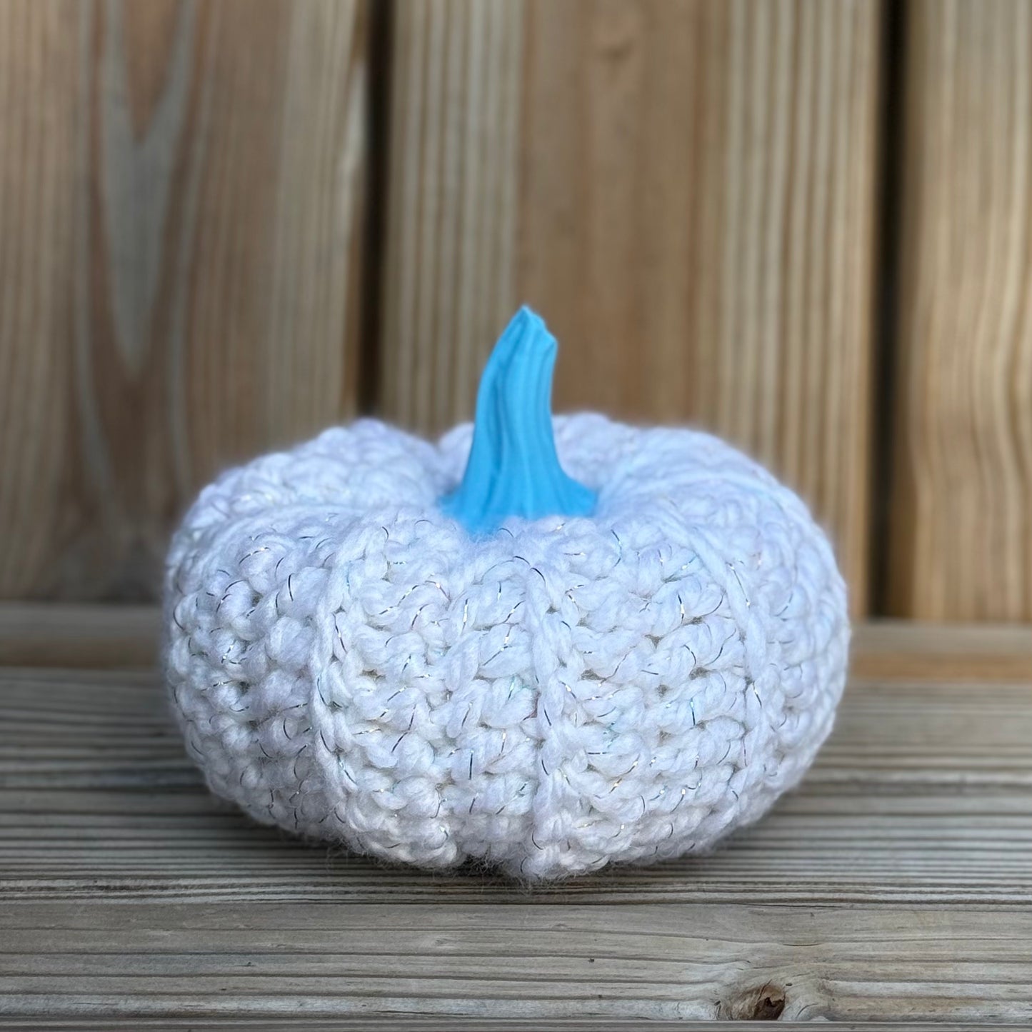 Knitted pumpkin with a blue stem on a wooden surface