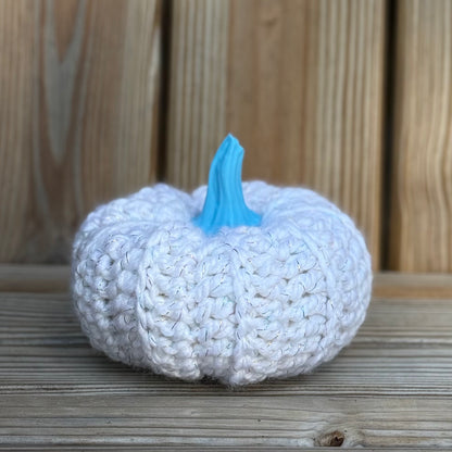 Knitted pumpkin with a blue stem on a wooden surface