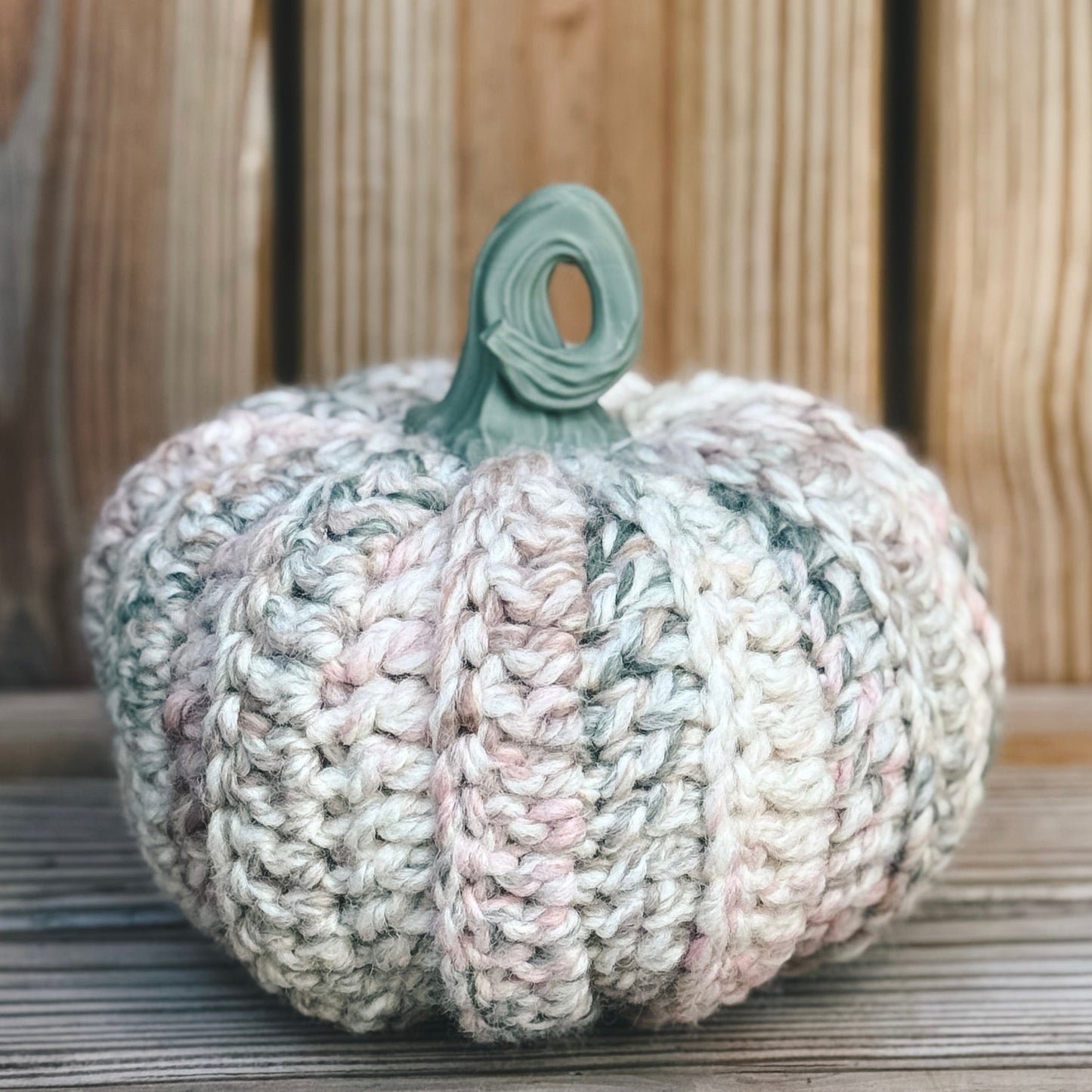 Knitted pumpkin decoration on a wooden surface with a wooden background