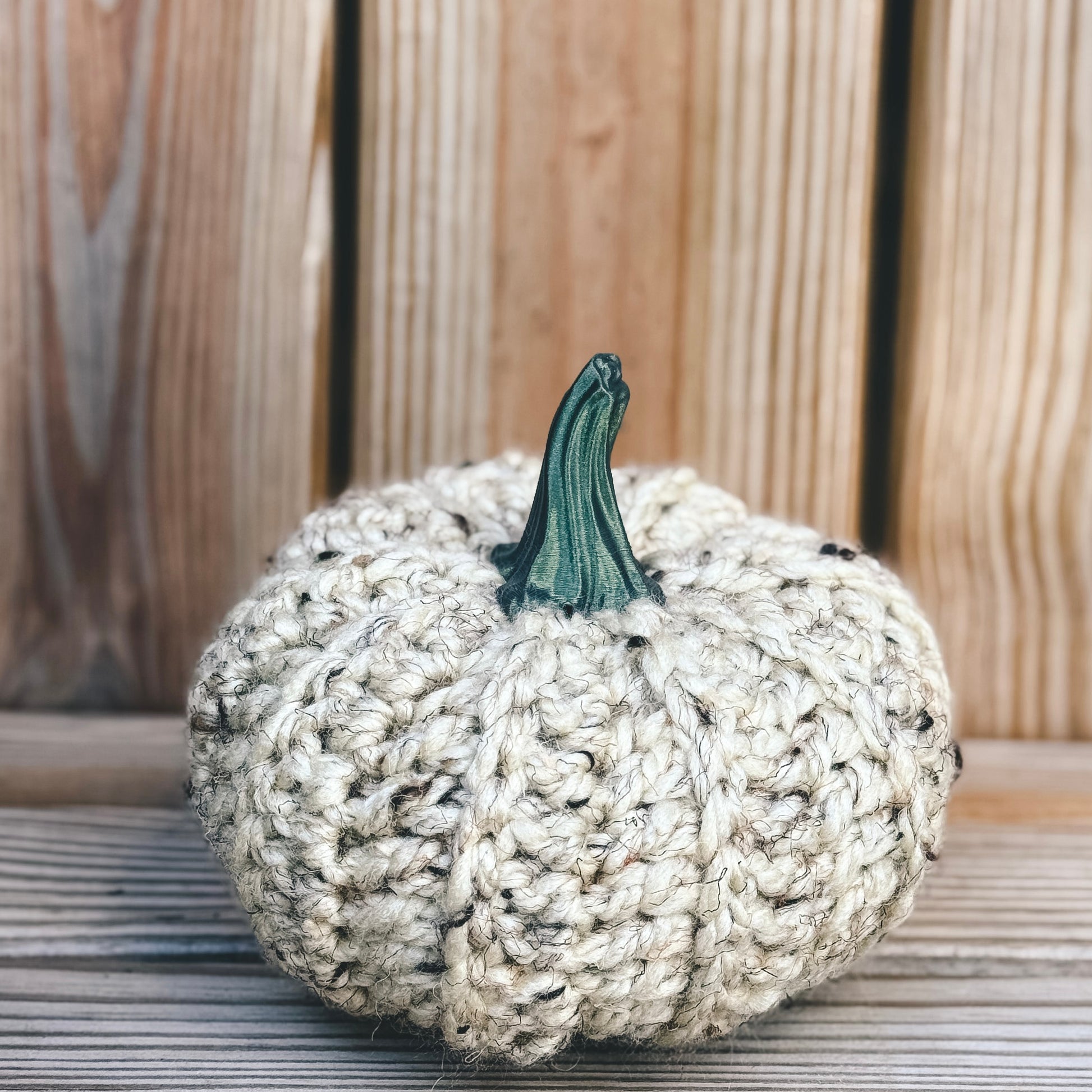 Knitted pumpkin with a green stem on a wooden surface