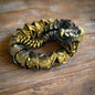 Gold rattlesnake with intricate design on a wooden surface
