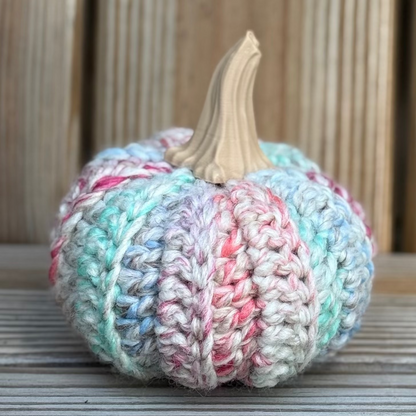 Knitted pumpkin with pastel colors on a wooden surface