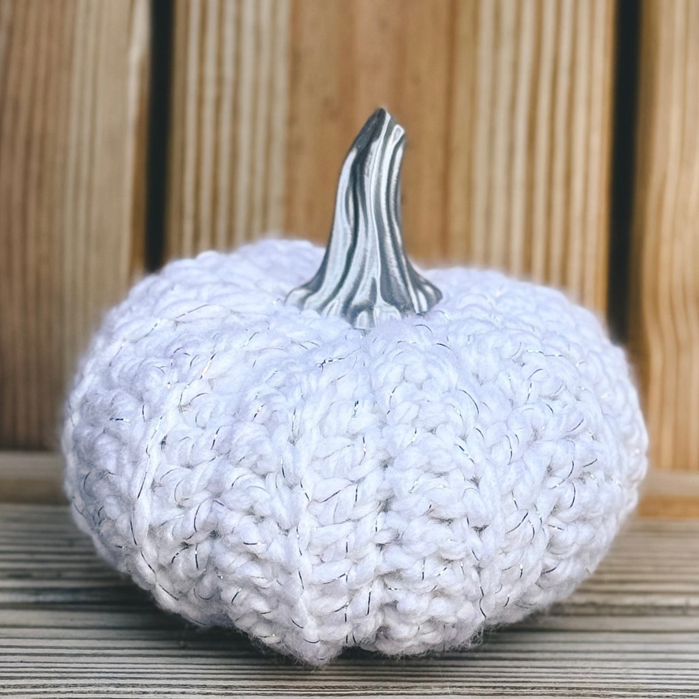 White textured pumpkin with a silver stem on a wooden surface