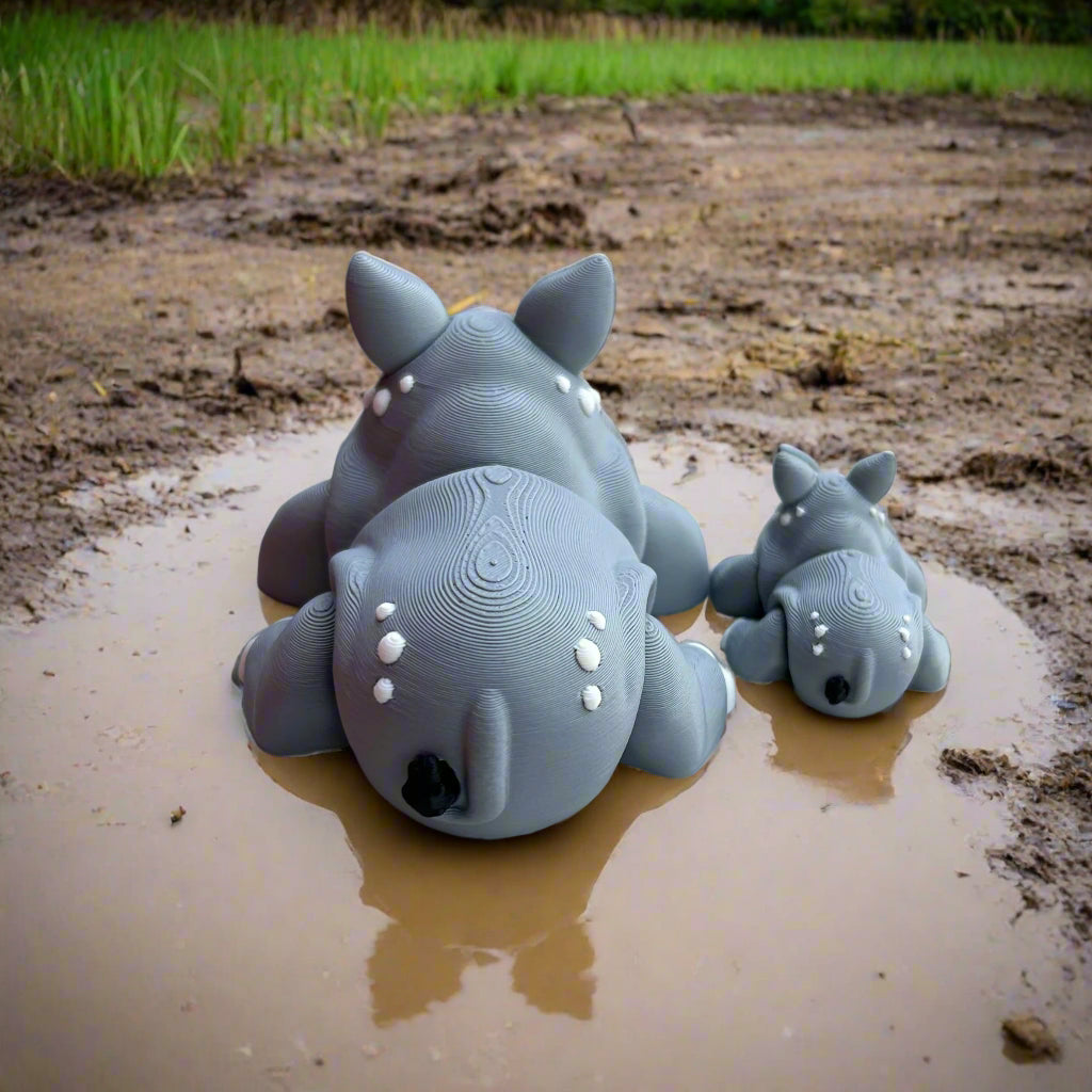 Two rinos sitting in a mud puddle backside